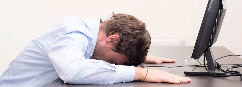 راهکارهای افزایش سرعت ویندوز 10- مرد از شدت ناراحتی به خاطر کند بودن ویندوز سر خود را روی میز قرار داده است